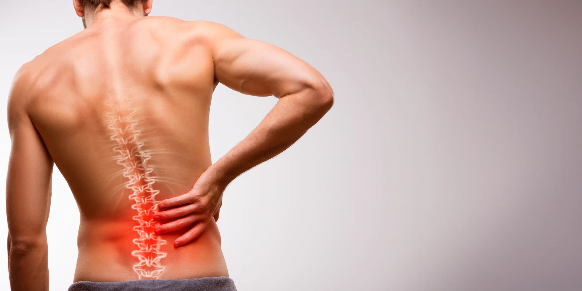 Chiropractic Clarksville TN Spinal Decompression A man holding his lower back. His spine is highlighted red to indicate pain.